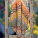 handknit striped baby blanket on a ladder