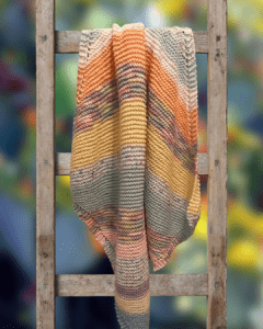 handknit striped baby blanket on a ladder