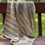 striped textured baby blanket draped on back of bench