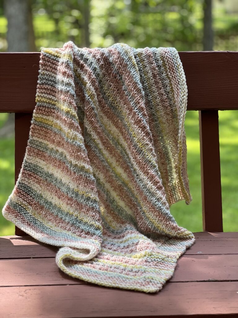 striped textured baby blanket draped on back of bench