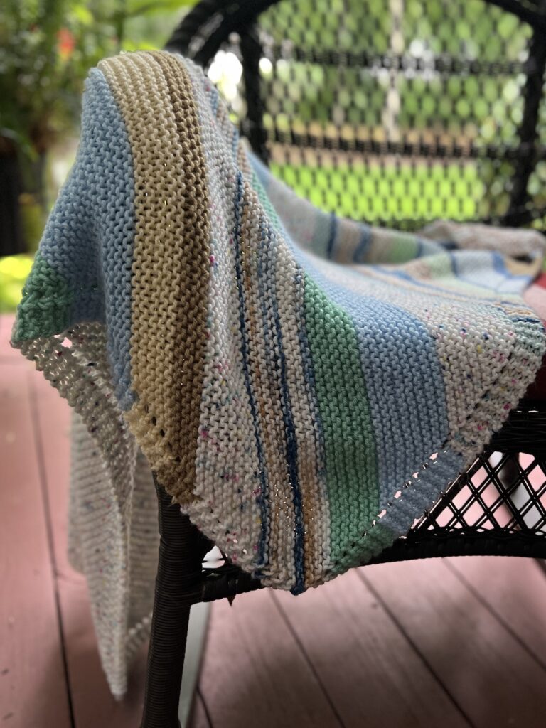 handknit striped blanket draped on wicker chari