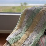 colorful blanket by the window with waves in the background