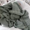 baby snuggled in teal textured blanket