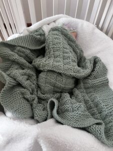 baby snuggled in teal textured blanket