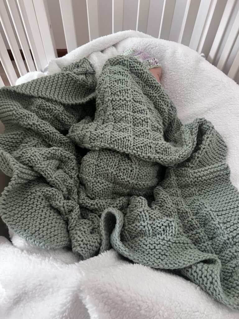 baby snuggled in teal textured blanket
