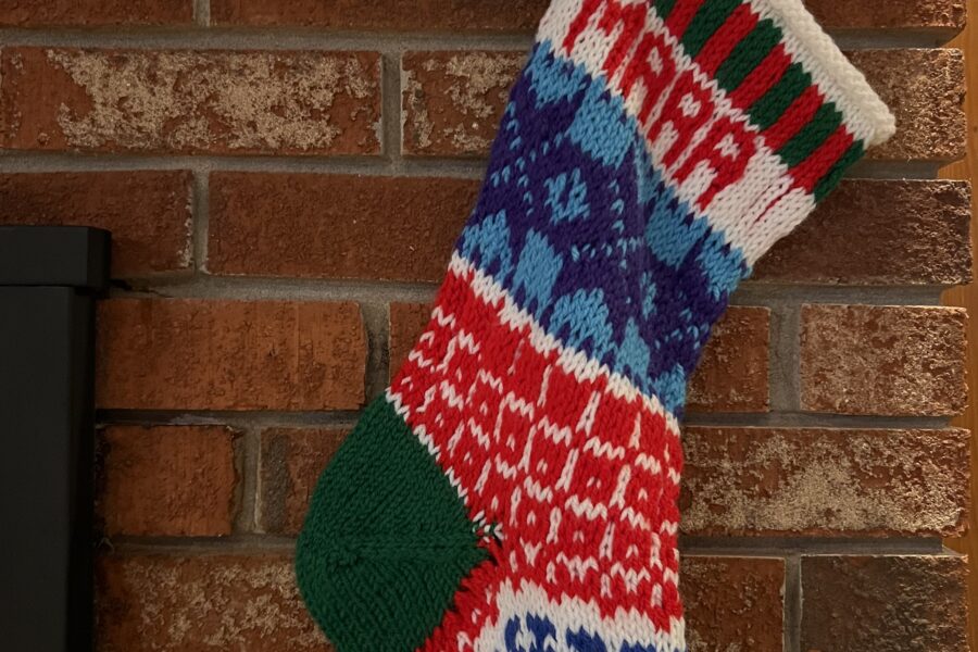 handknit christmas stocking hanging by chimney