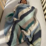 handknit baby blanket on baby in crib