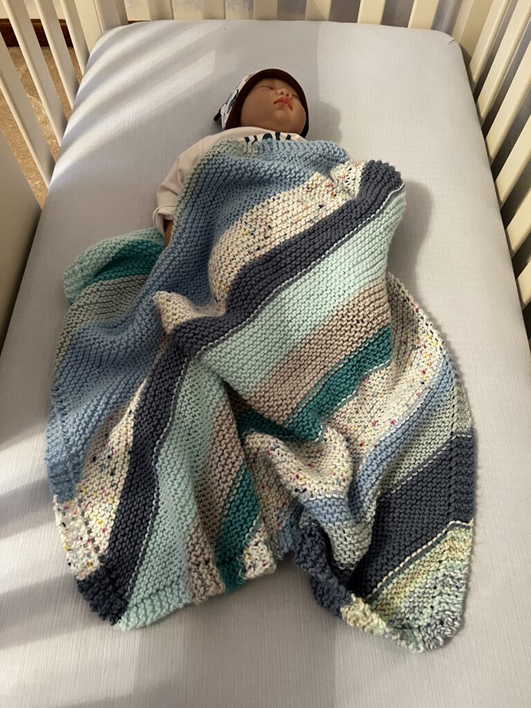 handknit baby blanket on baby in crib