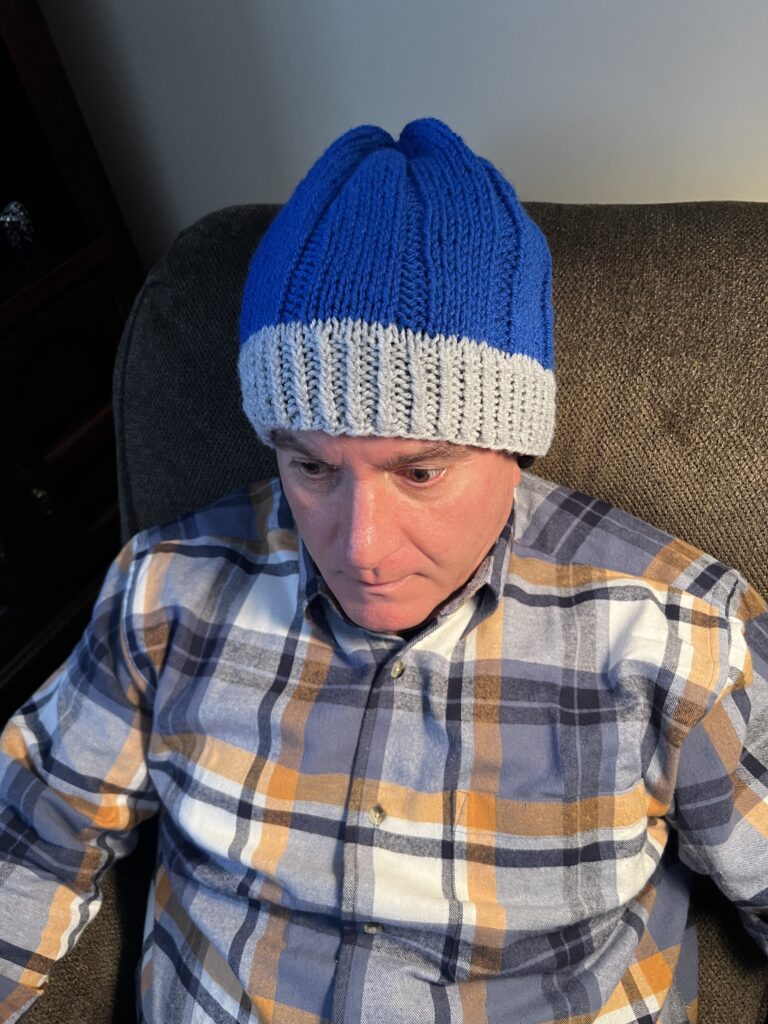 man with plaid shirt wearing grey and blue knit hat