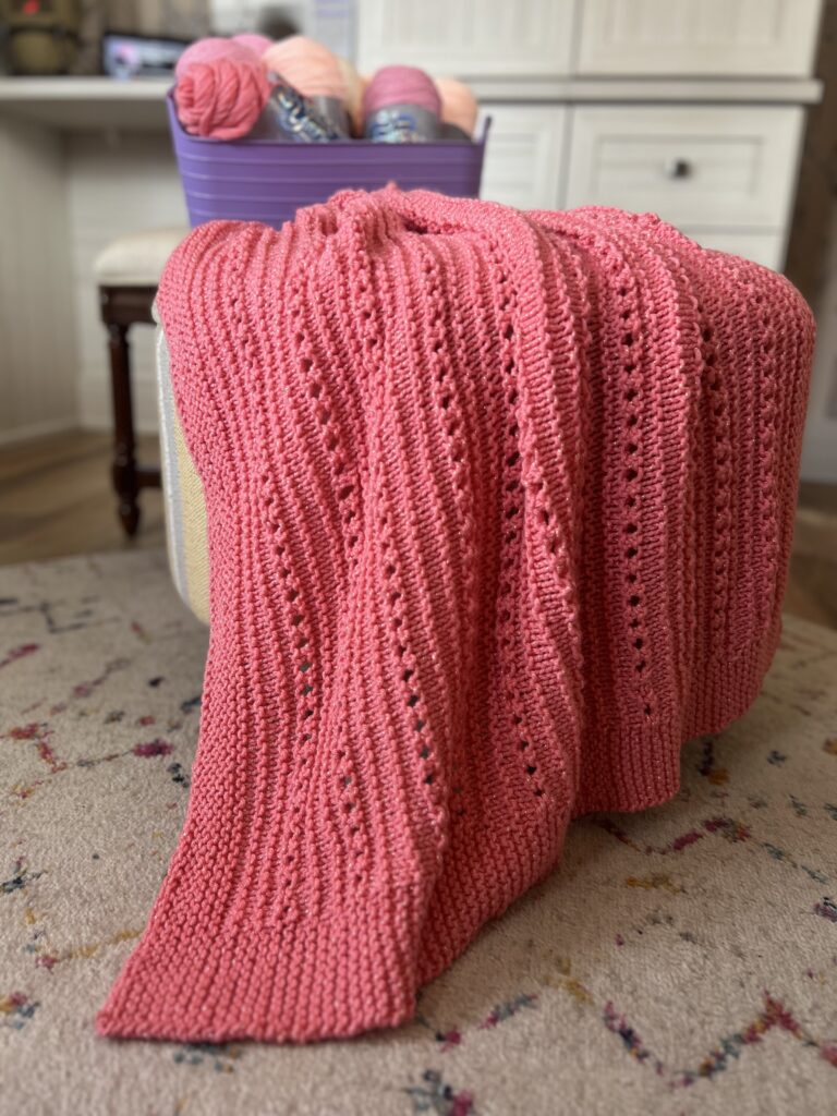 baby blanket draped on ottoman color coral
