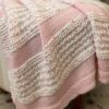 pink and white knit blanket draped on an ottoman
