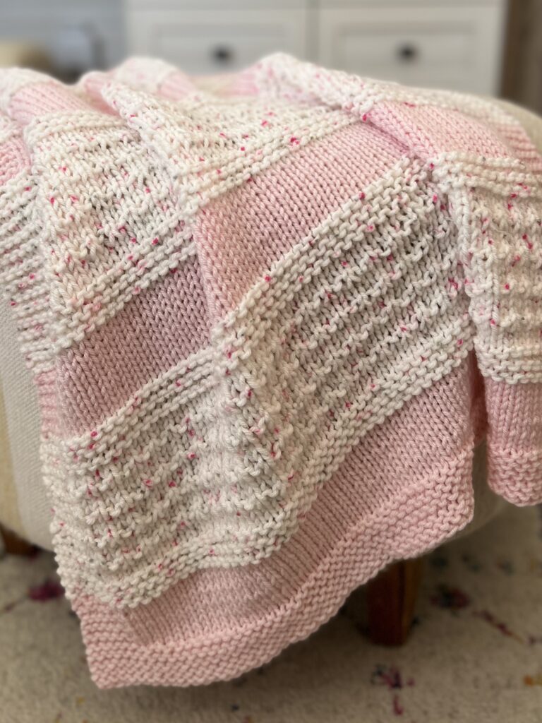 pink and white knit blanket draped on an ottoman