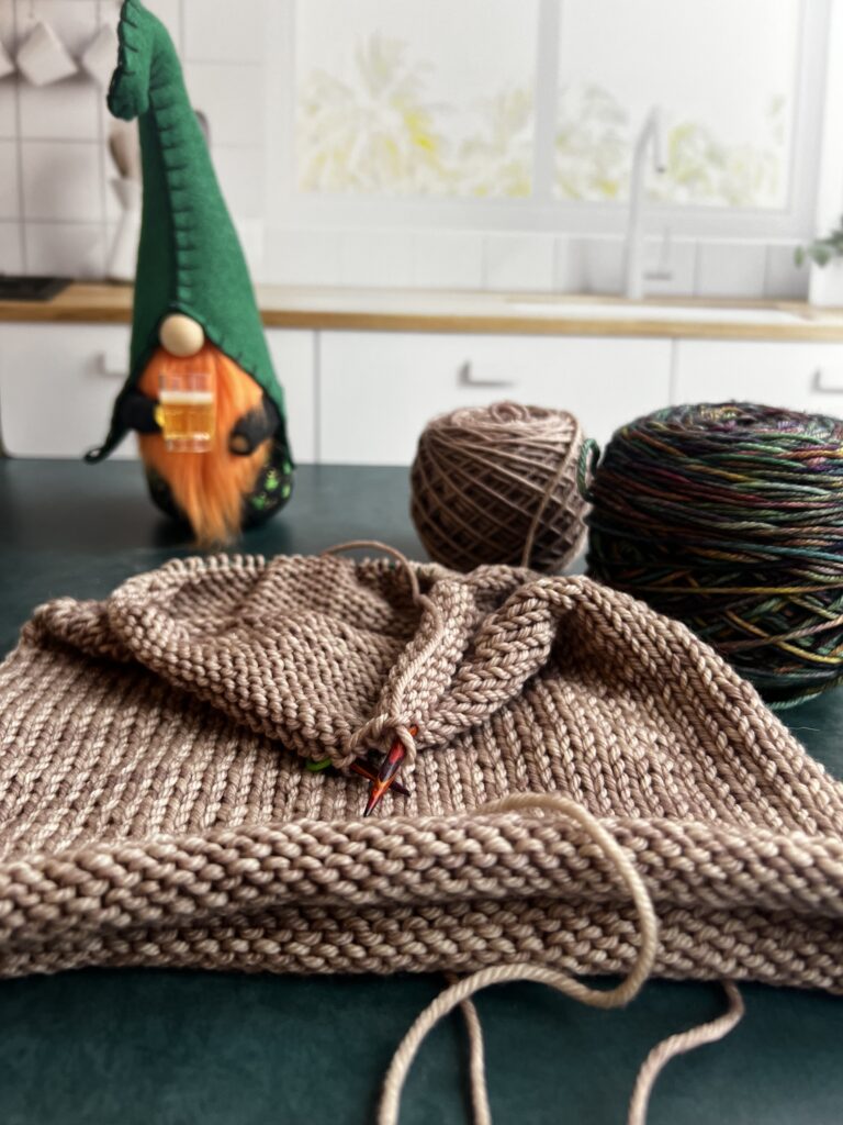 a gnome, yarn and an unfinished knit hat on a counter