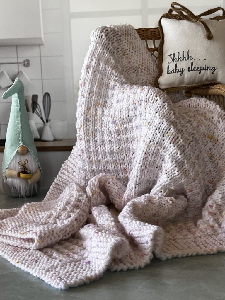 textured pink and white baby blanket draped on a chair