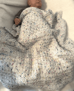 speckled hand knit blanket keeping baby warm