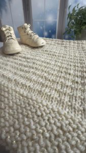 textured blanket and baby shoes