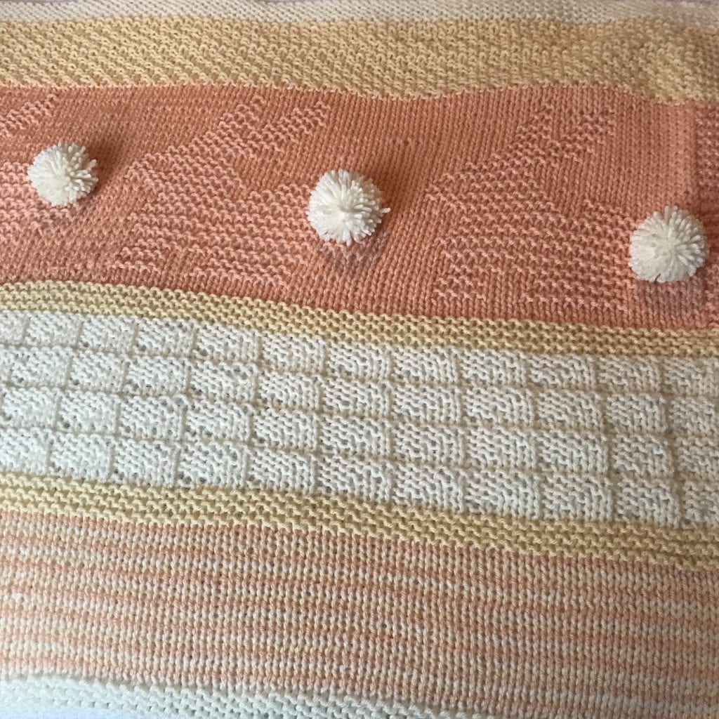 close up of yellow, white and peach baby blanket with bunny design