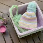 pink green and yellow hat in basket of yarn