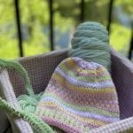 pink green yellow hat in pink gingham basket with green yarn