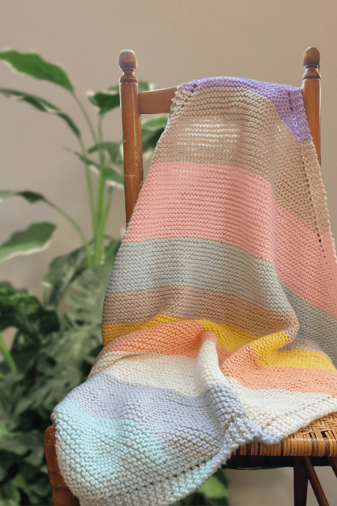 striped knit baby blanket on chair in front of plant