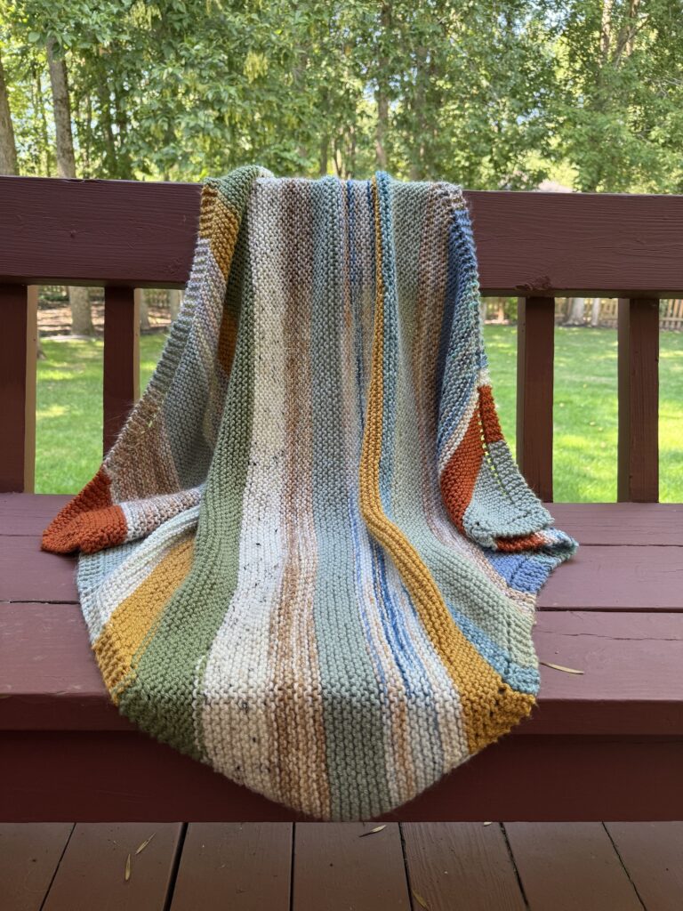 striped baby blanket draped on redwood bench