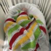 sleeping baby covered by colorful knit blanket in their crib