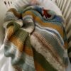 striped baby blanket draping baby in crib