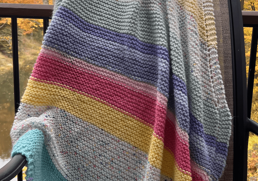 striped baby blanket on chair with fall leaves background