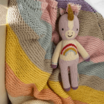 baby sleeping with knit doll and striped blanket
