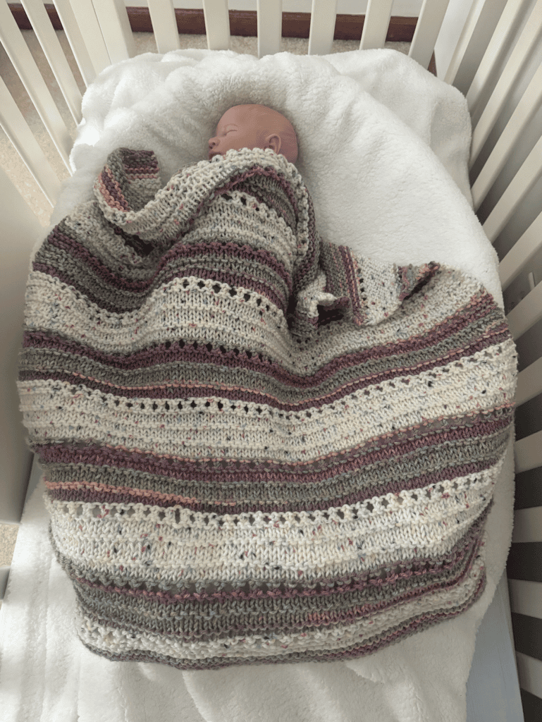knit blanket on baby in crib