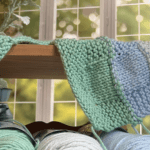 green blue and aqua blanket on a bench in front of window