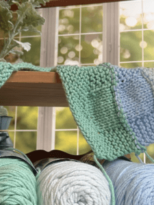 green blue and aqua blanket on a bench in front of window