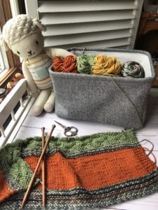 Knit blanket with basket of yarn and knit doll