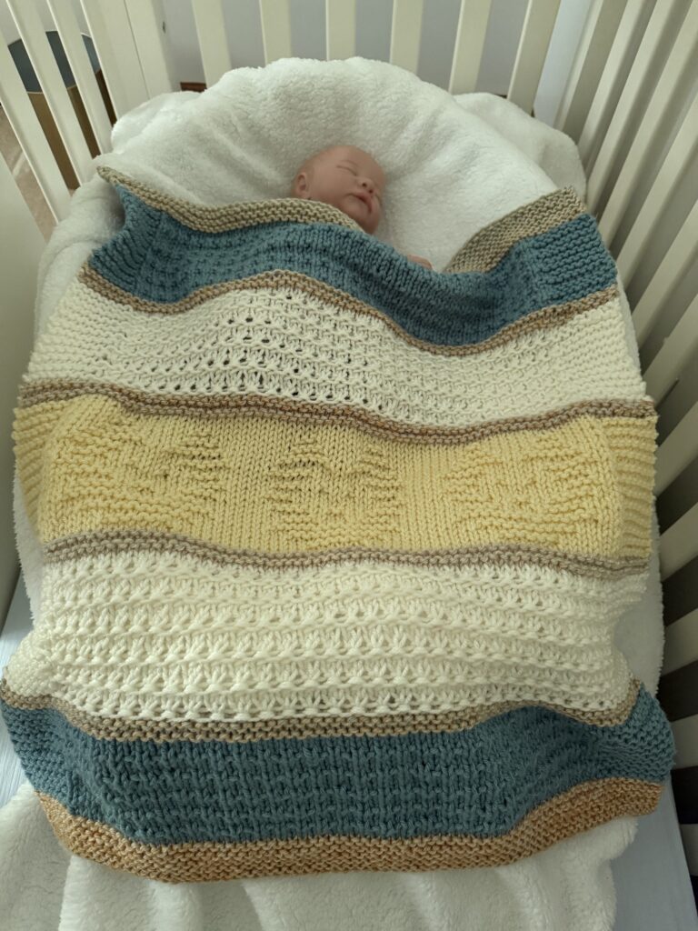 handknit blanket with lion cubs on baby in crib