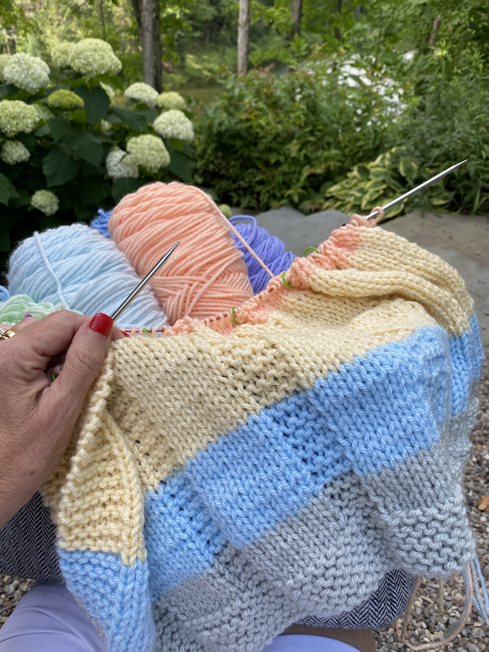 hand holding pastel striped blanket knitting in progress