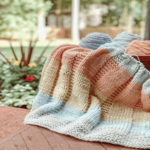 handknit striped blanket with flowers in the background