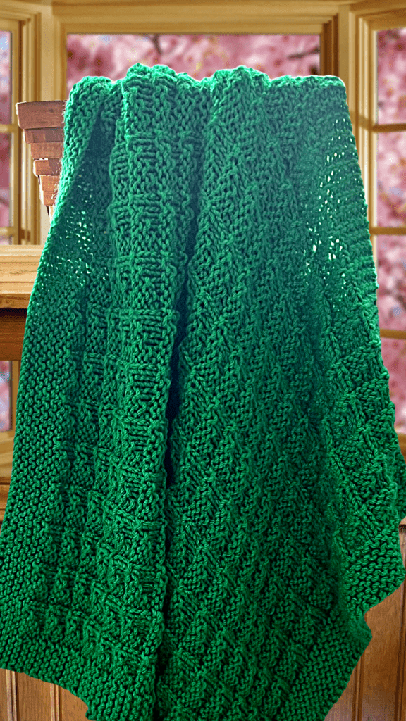 green baby blanket draped in front of window