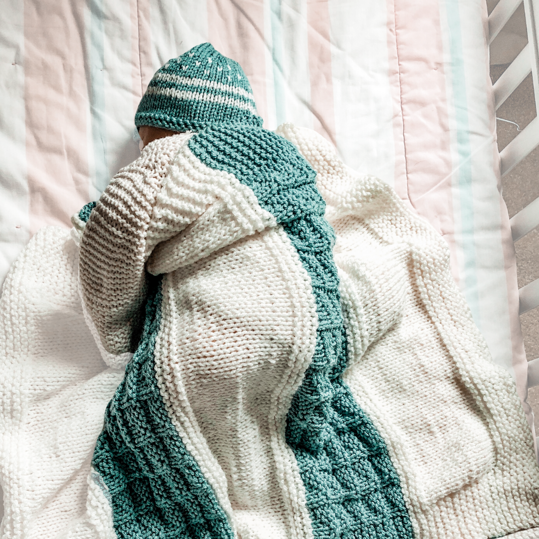 baby sleeping with aqua and cream knit blanket