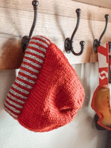 red hat with red/grey striped brim hanging on hook