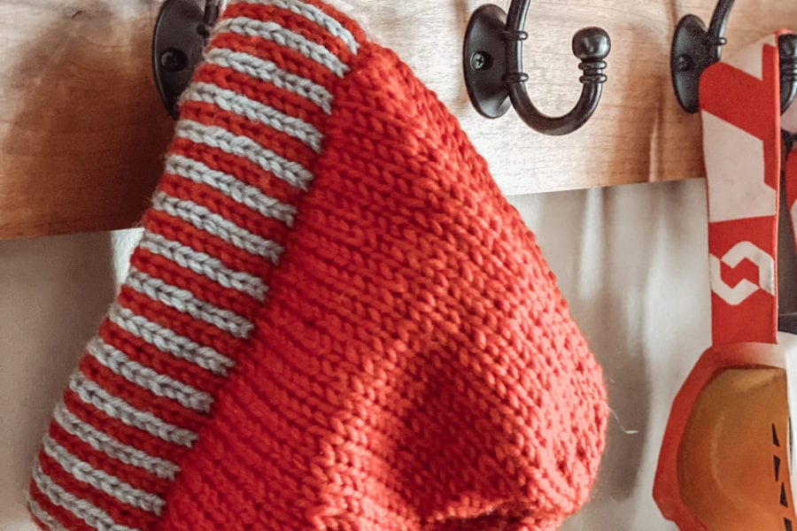 red hat with red/grey striped brim hanging on hook