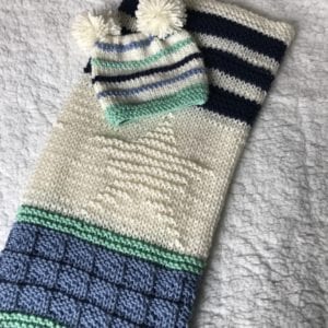 folded baby blanket with matching knit hat and 2 pompoms