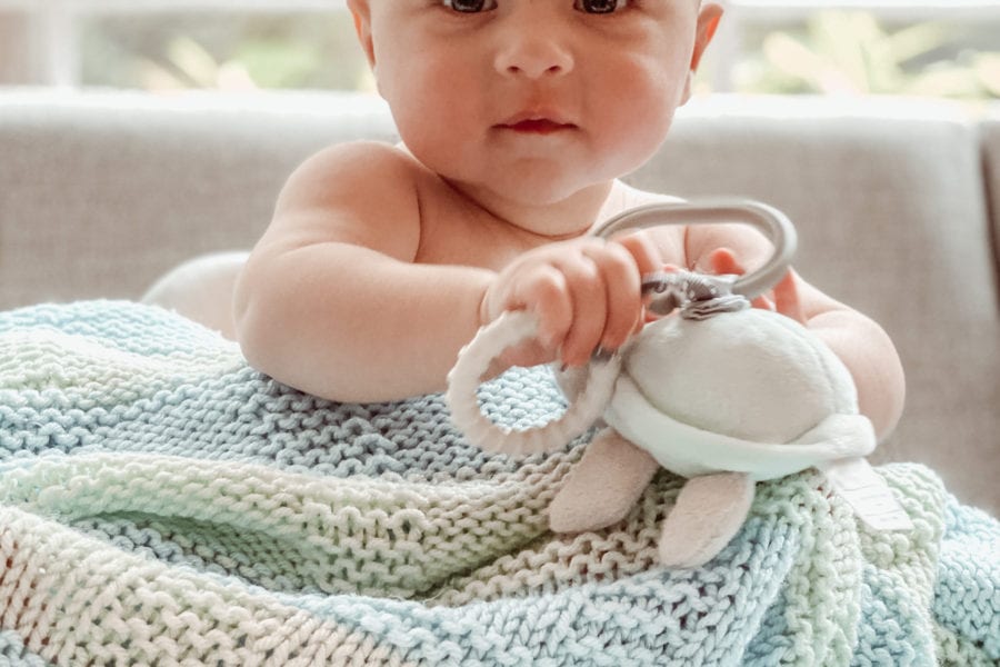 baby with toy and knit blanket