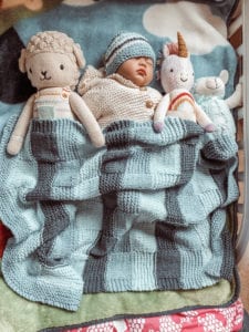 baby with dolls and blanket