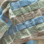 blue, green, gray basketweave baby blanket on ladder