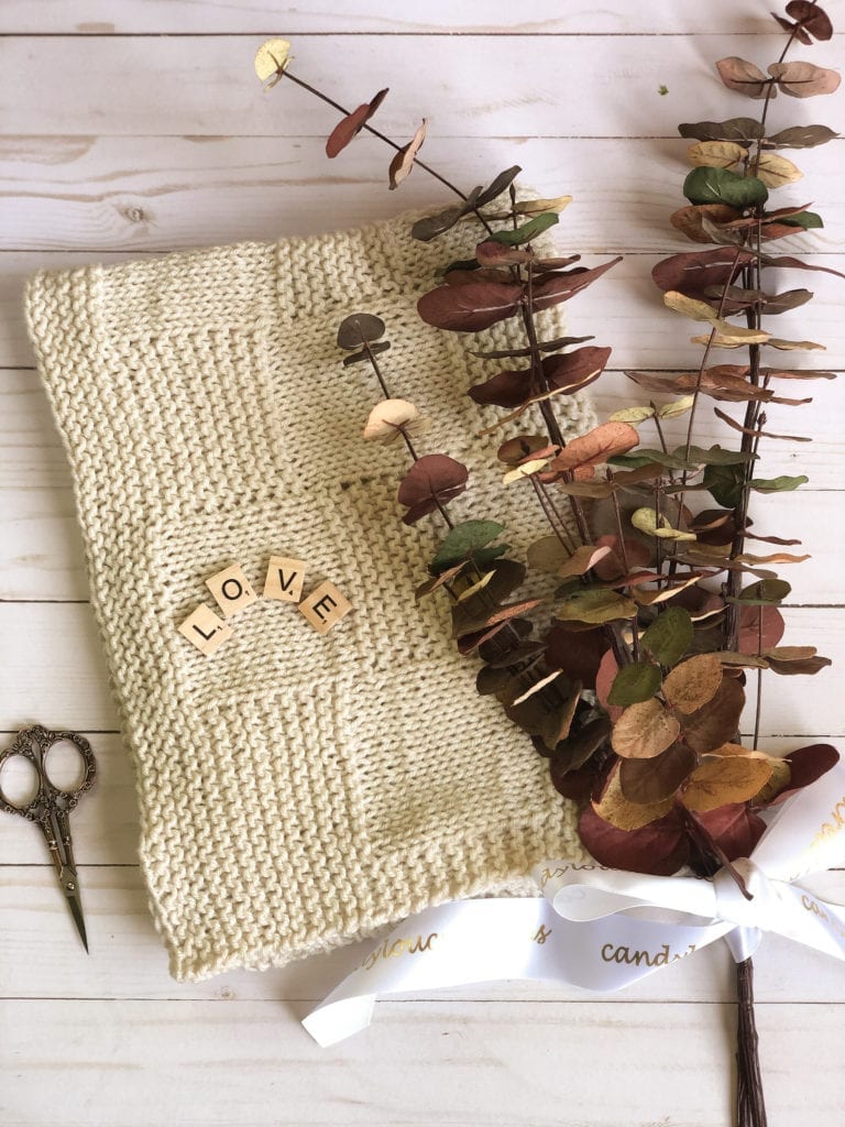 folded tan blanket with scissors and eucalyptus