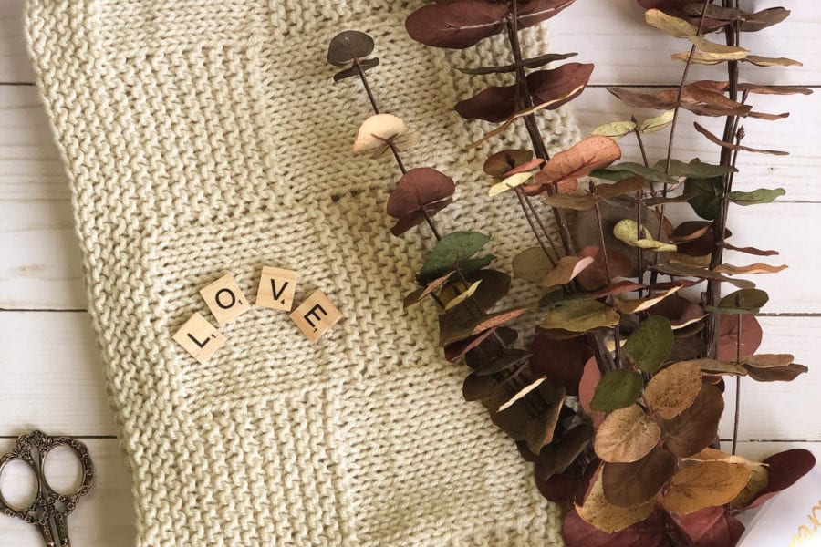 folded tan blanket with scissors and eucalyptus